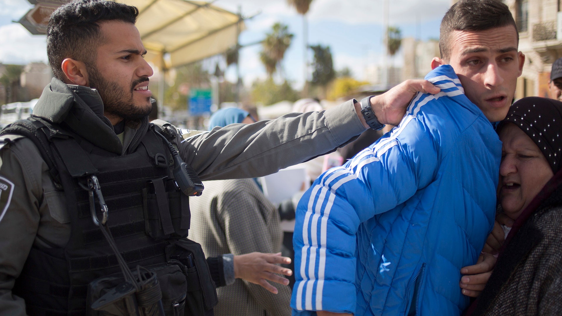 An Israeli border police officer pushes away Palestinian protesters outside the Damascus Gate in Jerusalem Old City, December 7