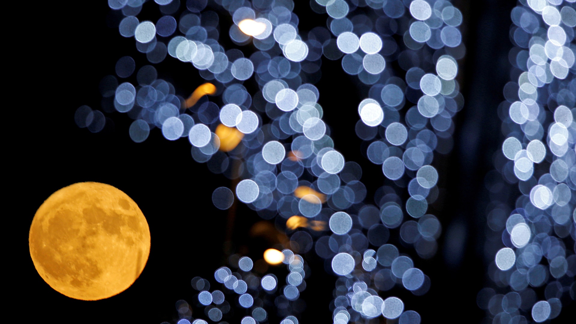 The full moon is pictured behind Christmas lights in Marseille, France, December 3