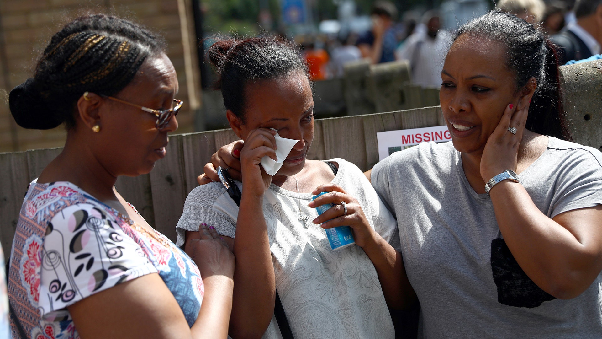 A woman is comforted as they stand near the destroyed apartment building in London
