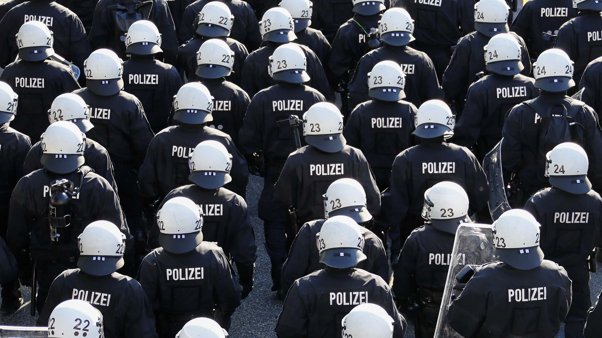 German riot police stand in front of protesters during demonstrations at the G-20 summit in Hamburg, Germany