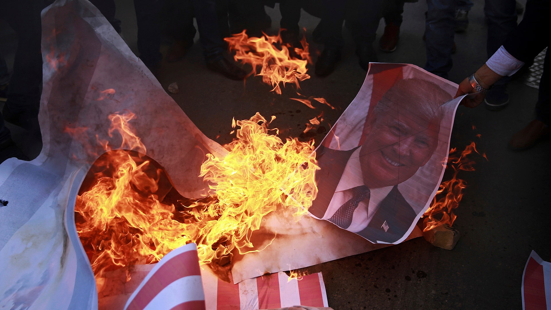 Palestinians burn a poster of U.S. President Donald Trump and a representation of an American flag, during a protest in Gaza City, December 7
