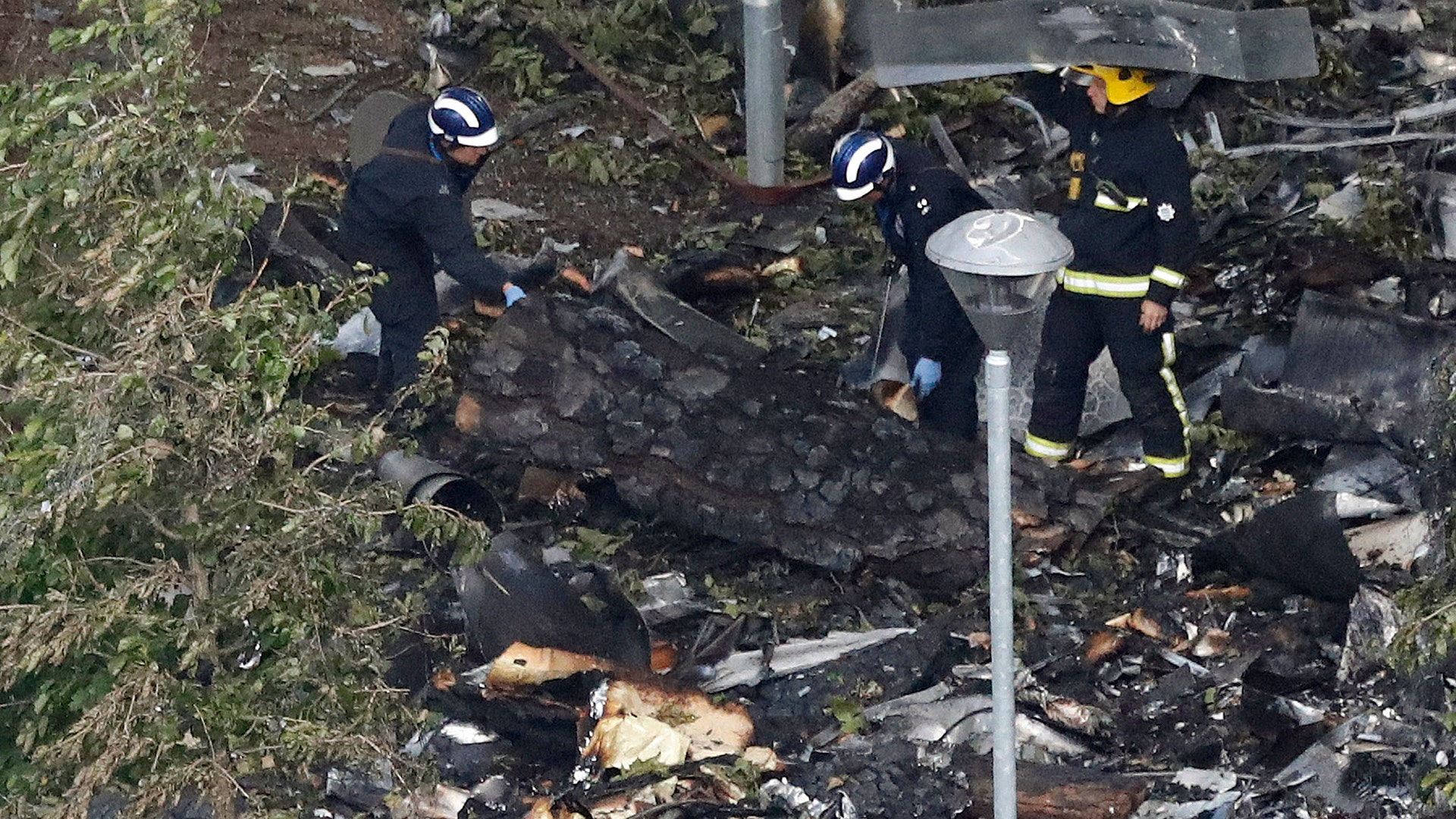 Firemen are shielded as they search through the debris scattered around the Grenfell Tower in London