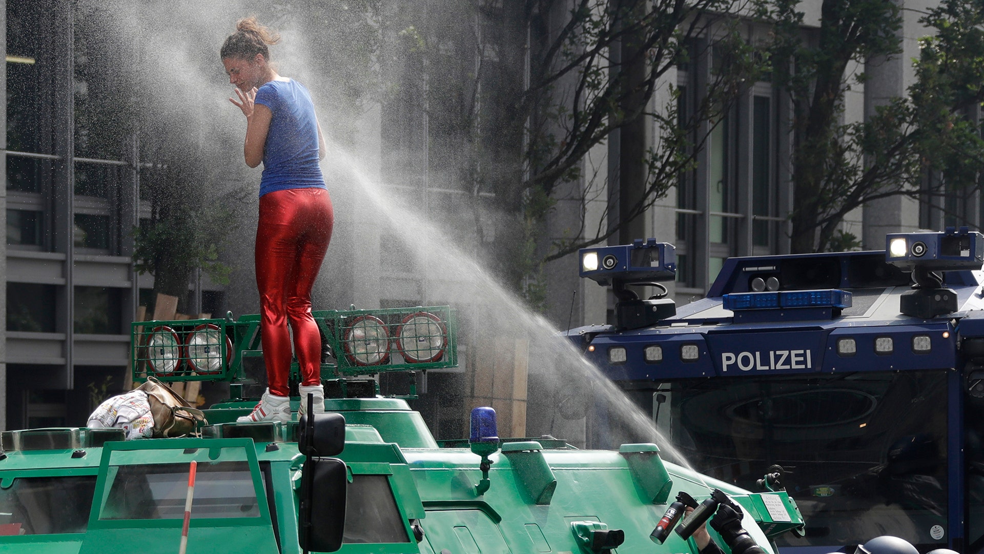 A woman is pepper-sprayed by police after she climbed on an armored police vehicle at the G-20 summit in Hamburg, Germany, Friday
