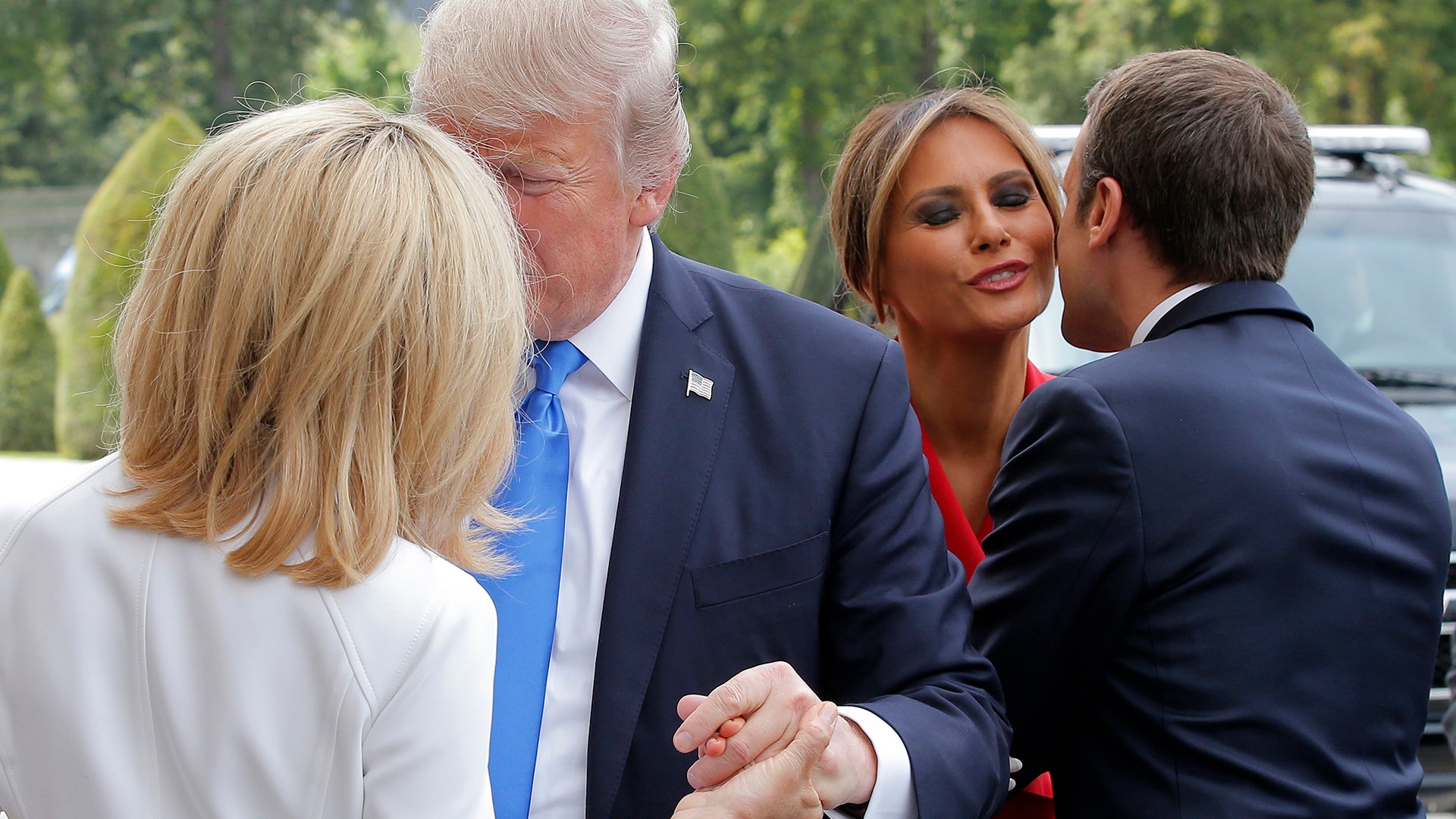 French President Emmanuel Macron kisses First Lady Melania Trump while his wife Brigitte welcomes President Donald Trump in Paris