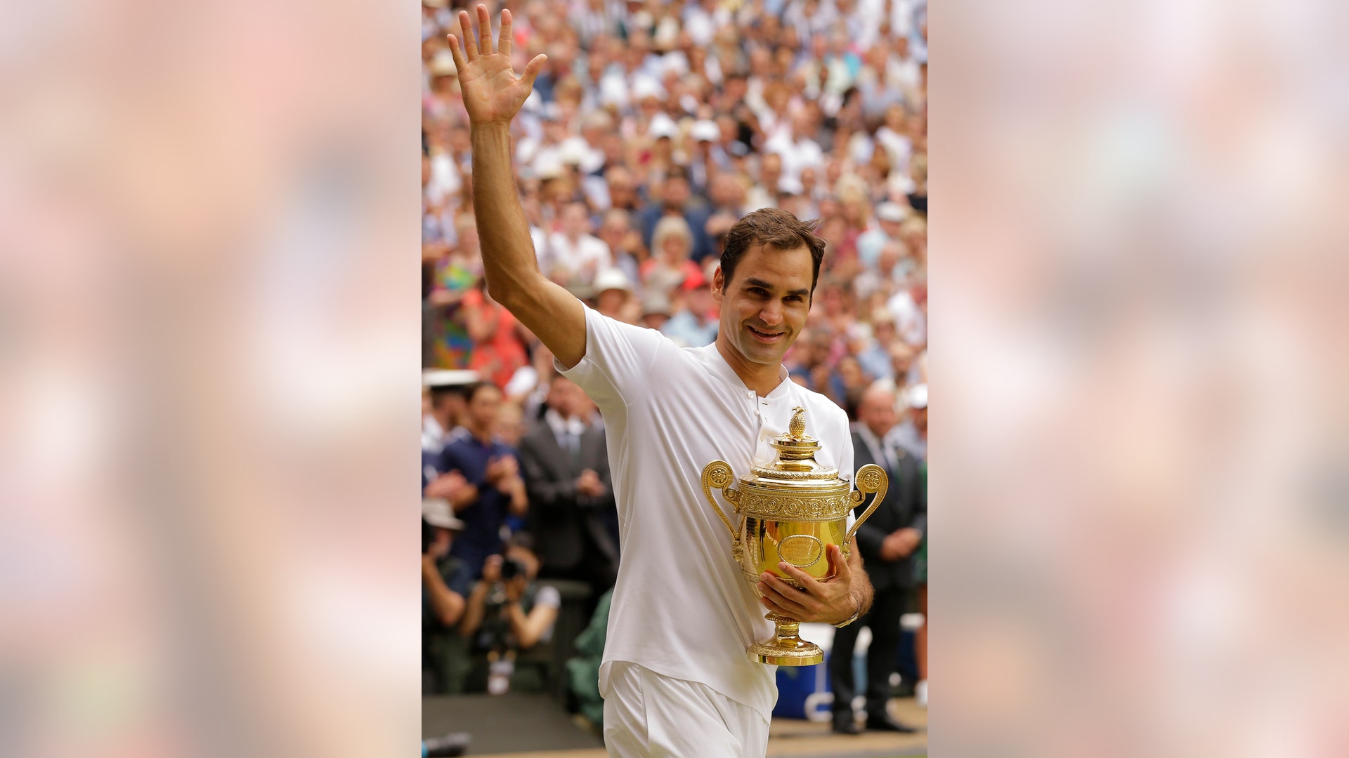 Switzerland's Roger Federer carries the trophy after defeating Croatia's Marin Cilic to win the Wimbledon men's singles title in London