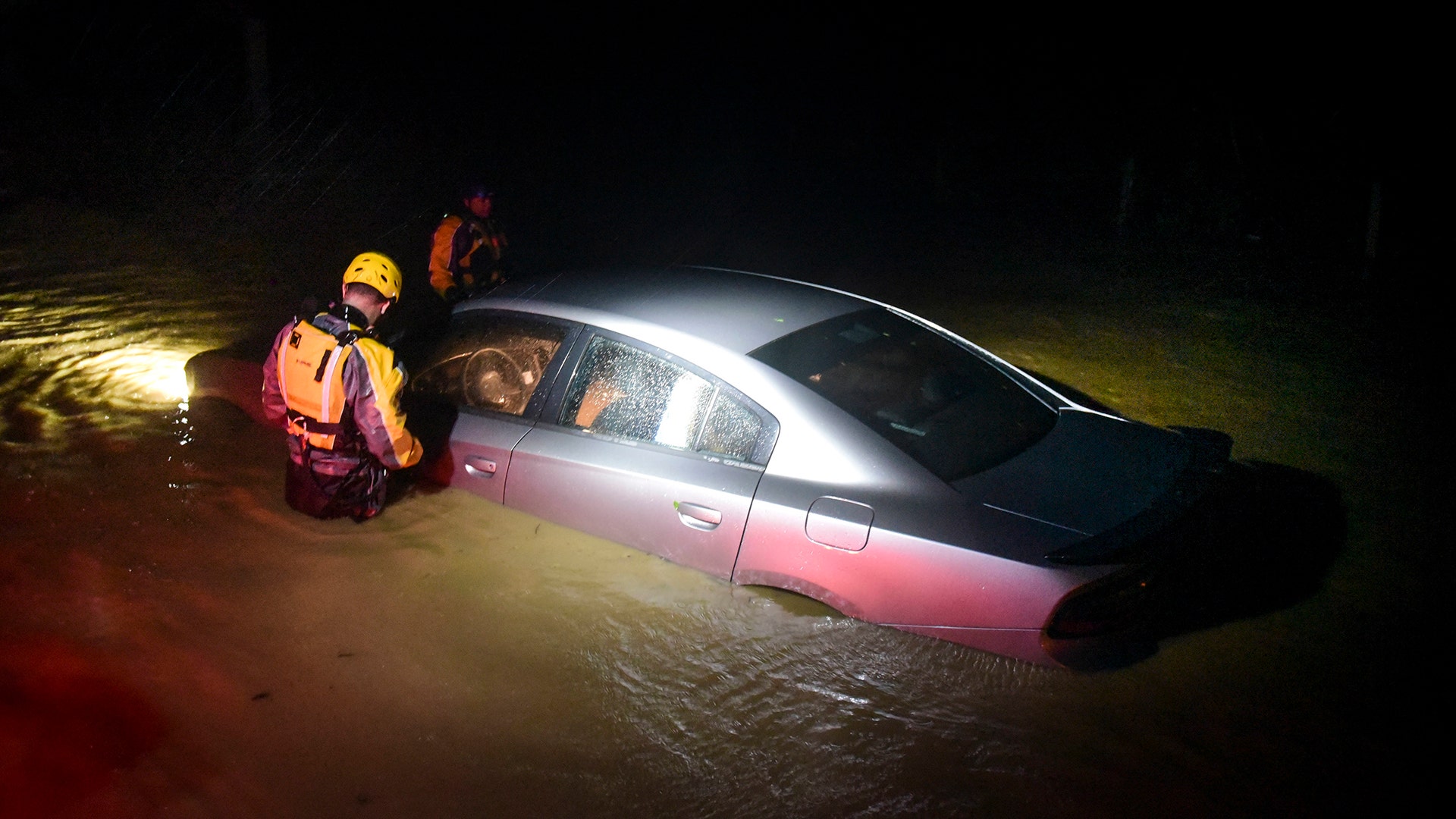 Rescue staff from the Municipal Emergency Management Agency investigate an empty flooded car in Fajardo, Puerto Rico, Wednesday