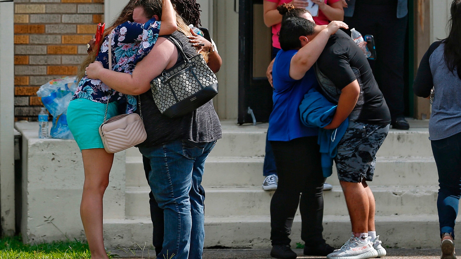 People embrace outside the Alamo Gym where students and parents reunited following a shooting at Santa Fe High School, May 18, 2018