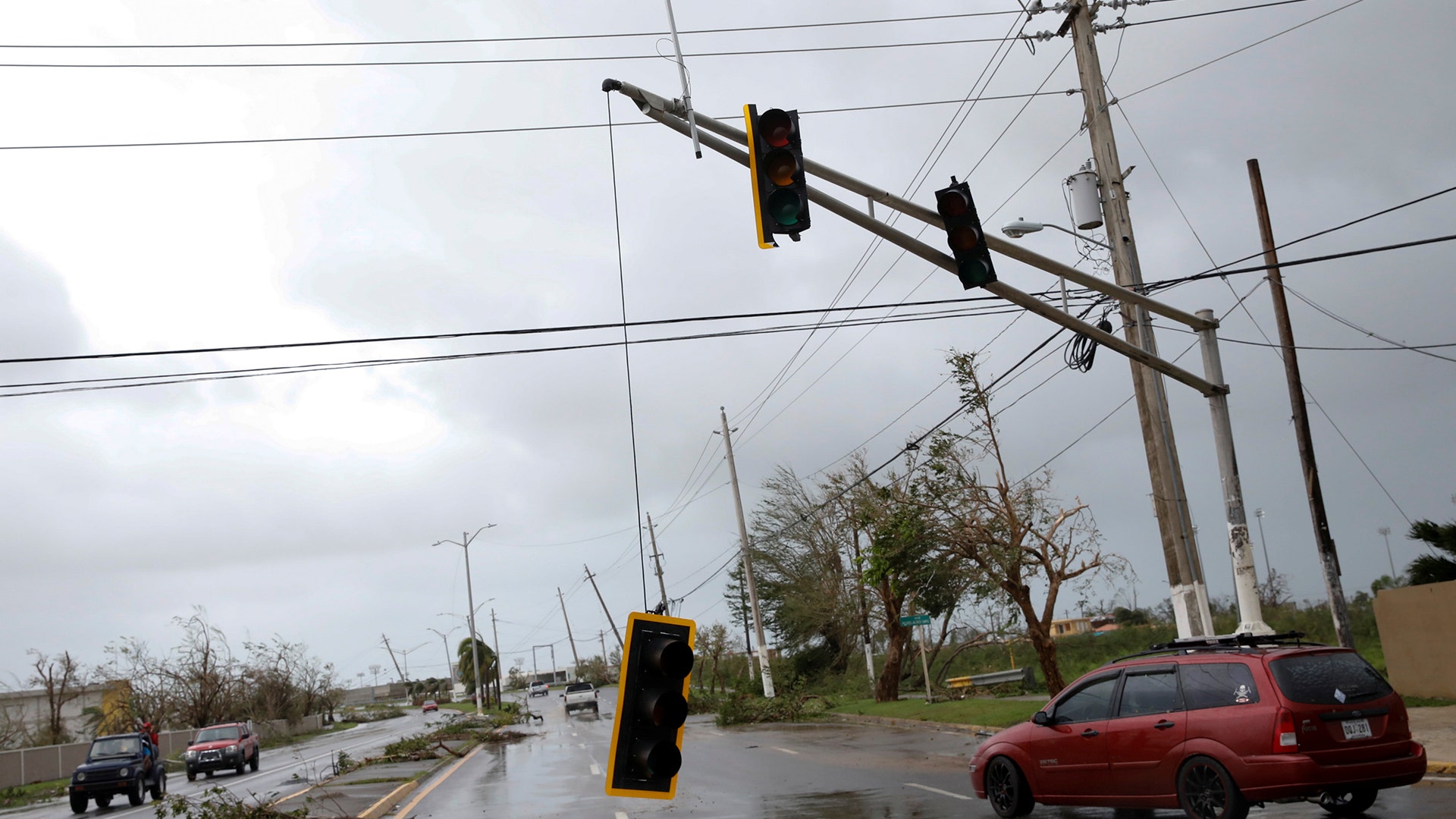 Cars drive past a damaged traffic light after the area was hit by Hurricane Maria in Guayama, Puerto Rico, Wednesday