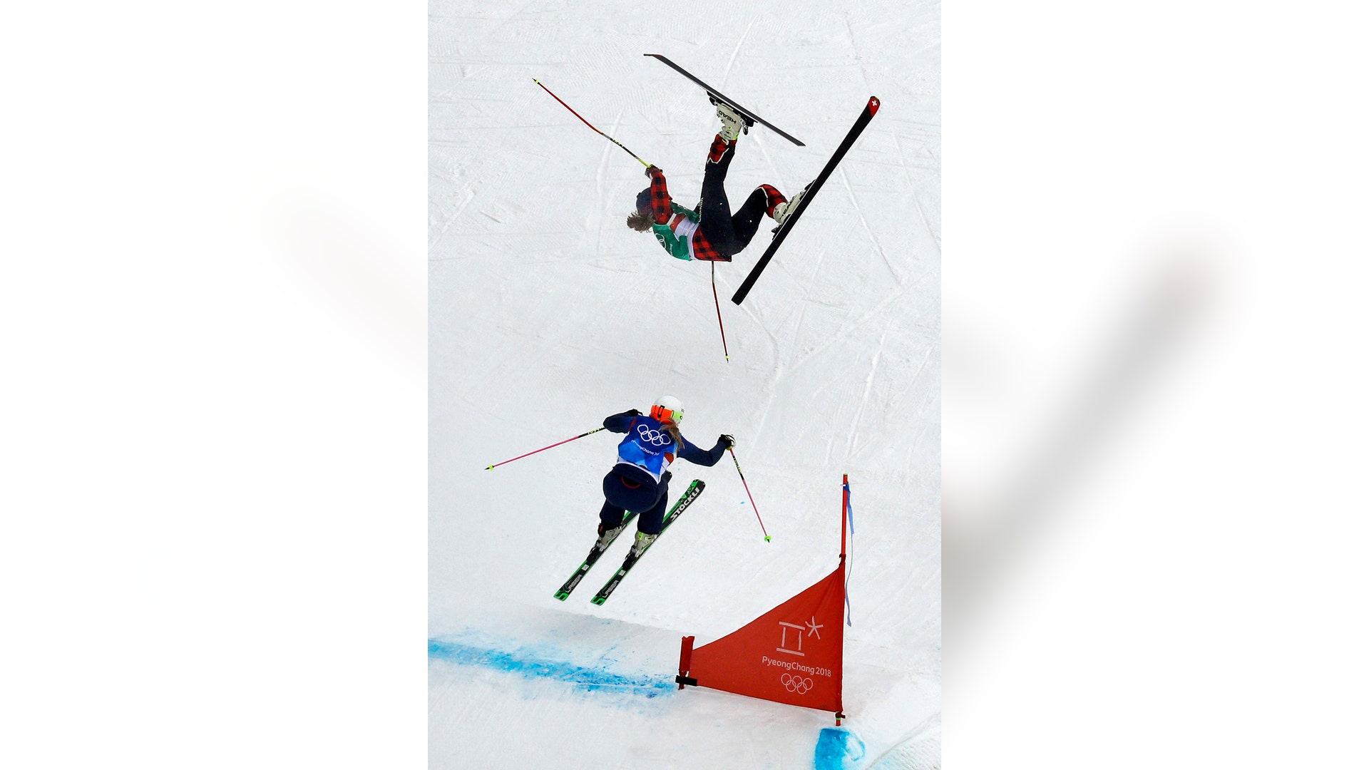 India Sherret of Canada, crashes as Emily Sarsfield of Britain, jumps during the women's ski cross elimination round at the Winter Olympics