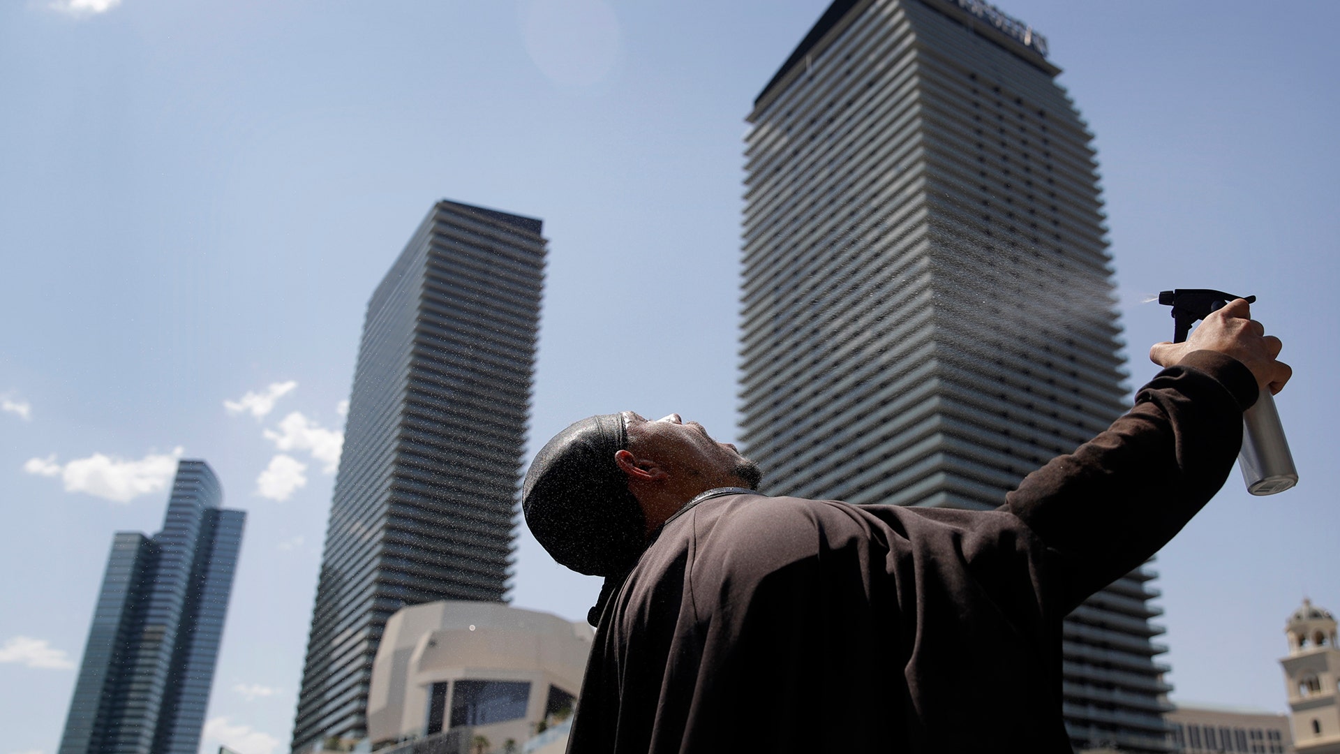Chris Mitchell sprays water on his face to cool off in a Darth Vader costume along the Las Vegas Strip, Tuesday