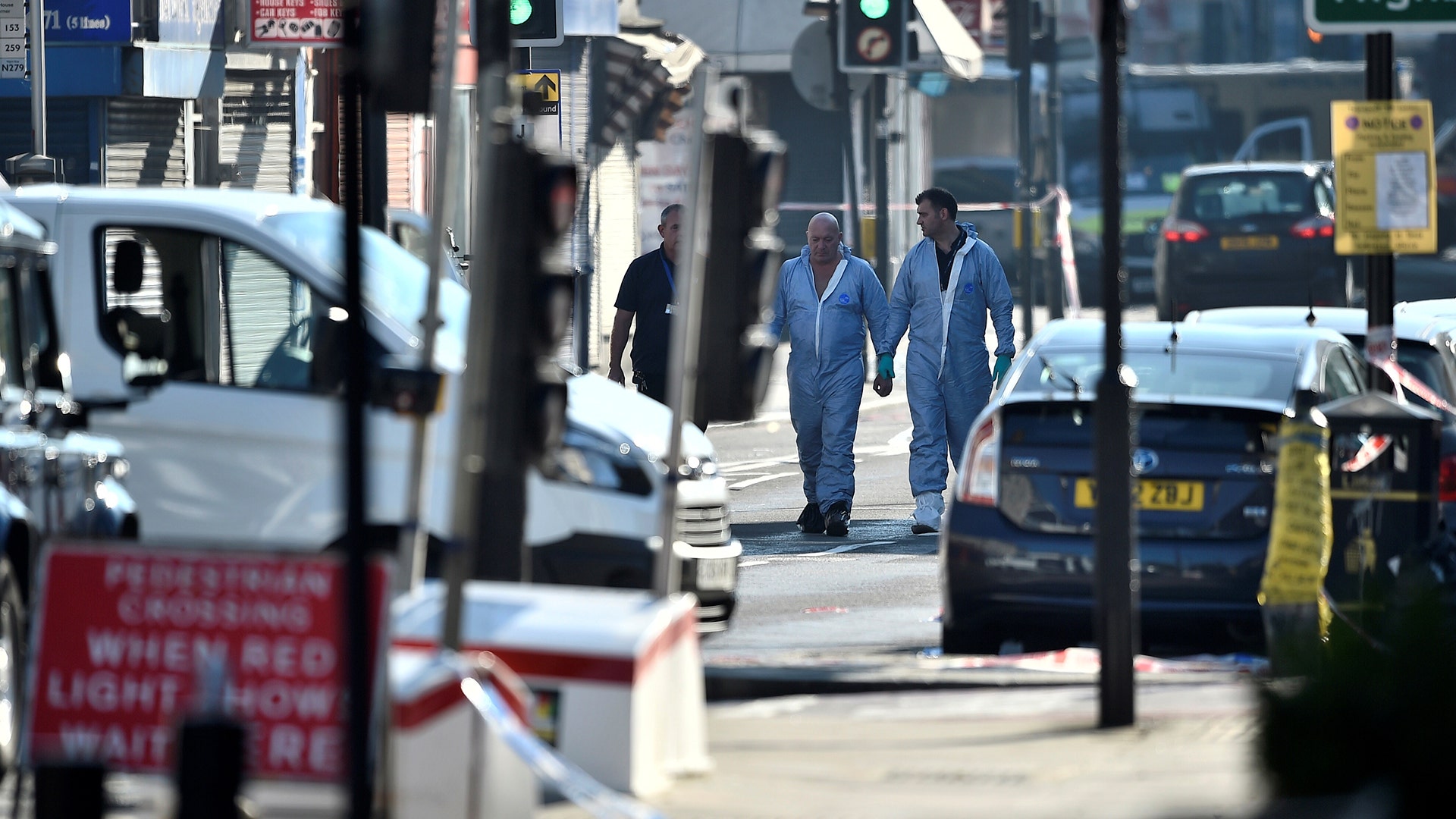 Police forensic officers walk down a road close to where a vehicle collided with pedestrians in the Finsbury Park neighborhood of London