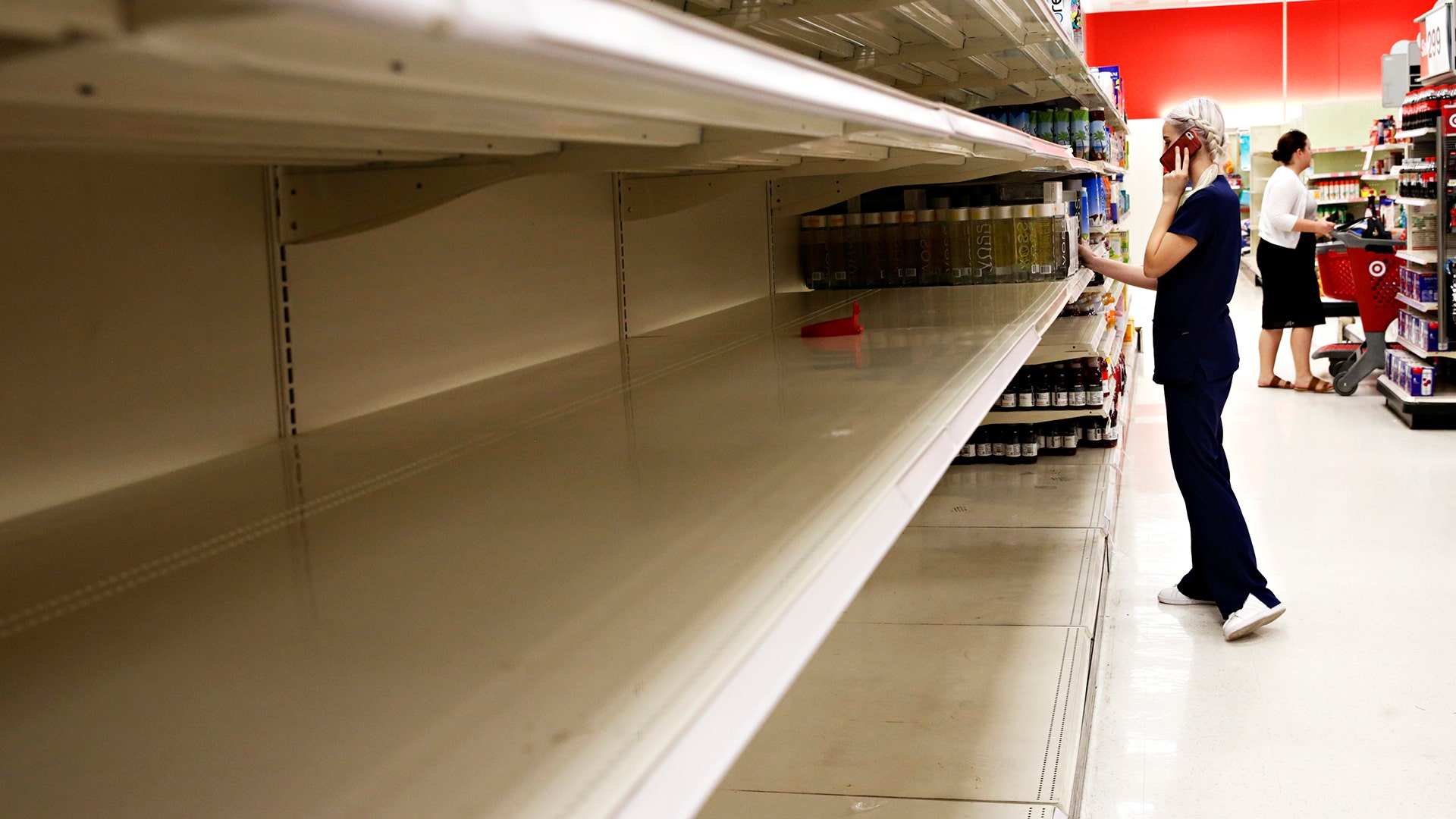 Kailey Coventry walks past empty shelves of water at Target in Gainesville, Fla., on Wednesday
