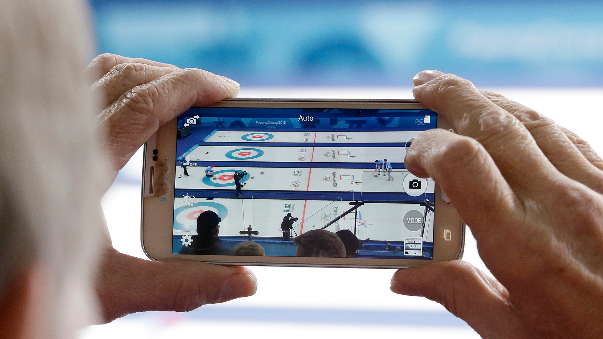 A man records the men's curling finals match between USA and Japan