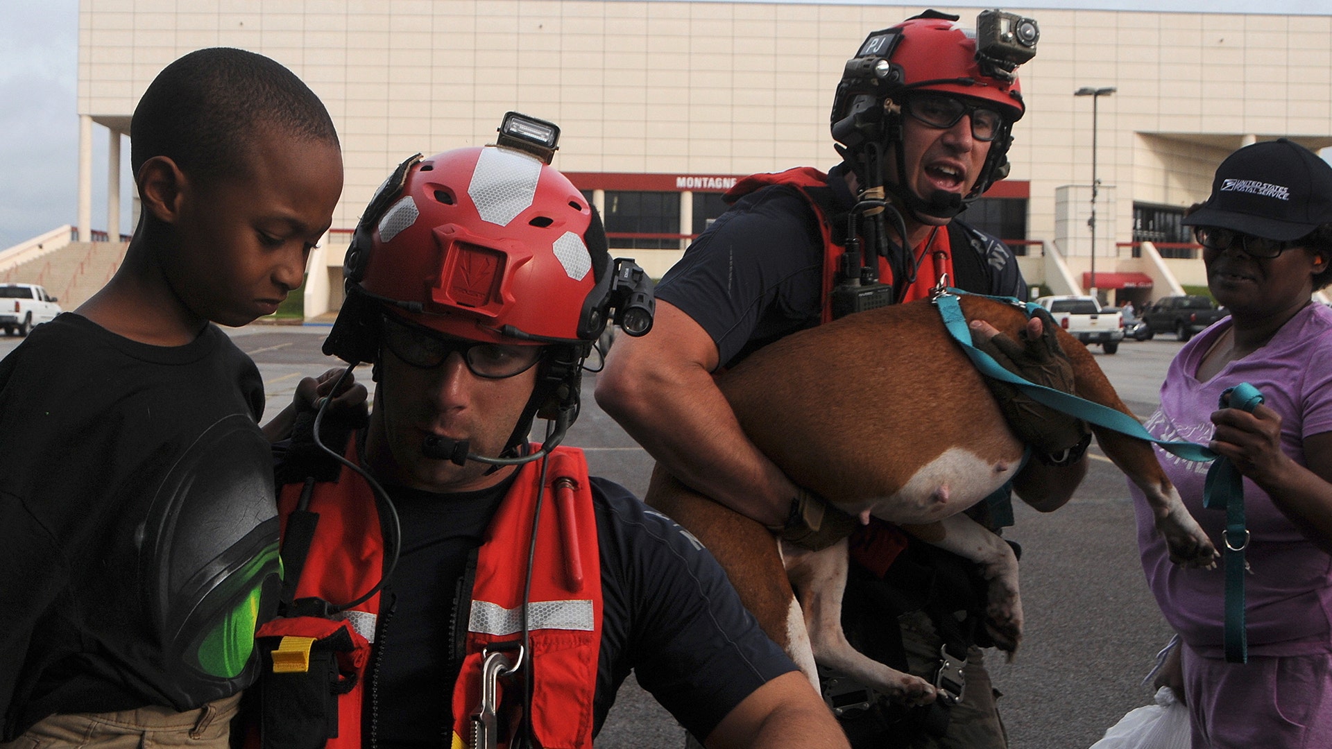 Senior Airman John J. Kosequat and Staff Sgt. Ryan R. Dush carry a child and dog off an HH-60 Pave Hawk helicopter