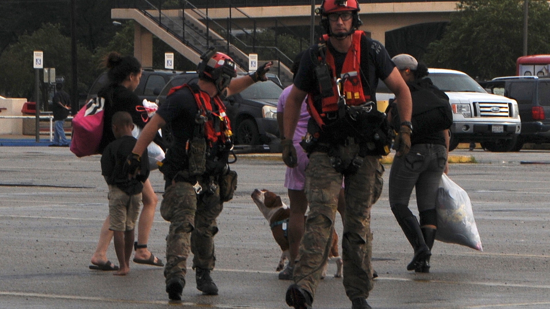 A pararescueman with the 103rd Rescue Squadron waves to a rescued group