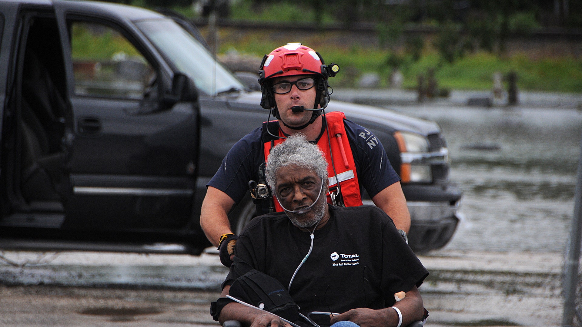 Senior Airman John J. Kosequat pushes an elderly man toward the HH-60 Pave Hawk helicopter