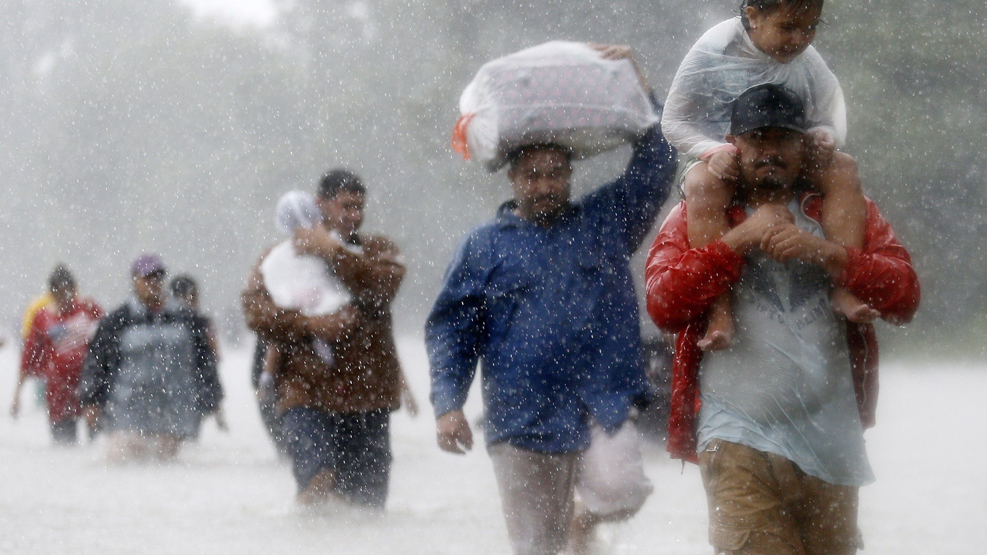 Residents wade through flood waters from Tropical Storm Harvey in Beaumont Place, Houston, Monday