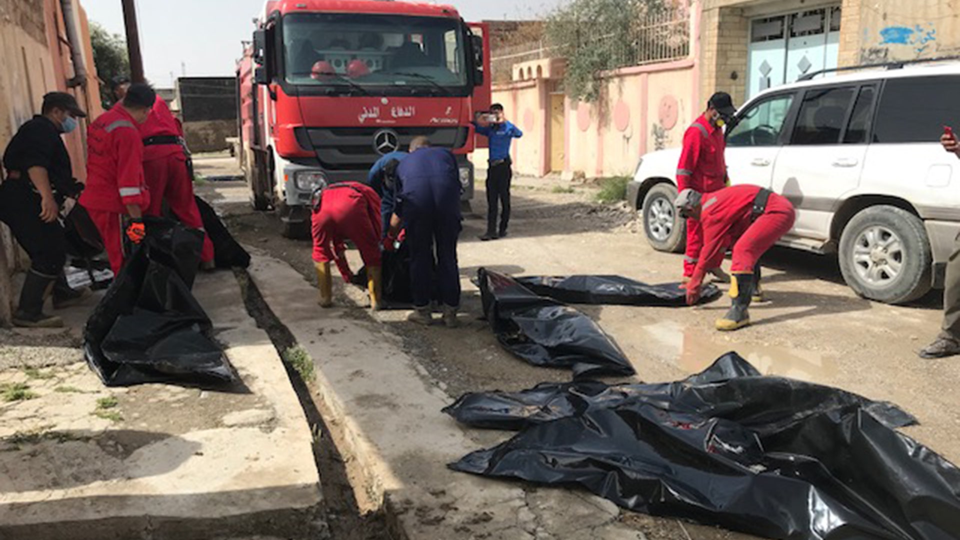 Recovery workers prepare to load the remains of ISIS victims, including two children found in mass graves onto trucks