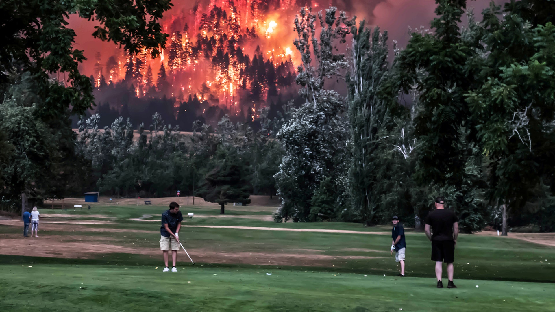 The Eagle Creek wildfire burns as golfers play at the Beacon Rock Golf Course in North Bonneville, Washington, September 4