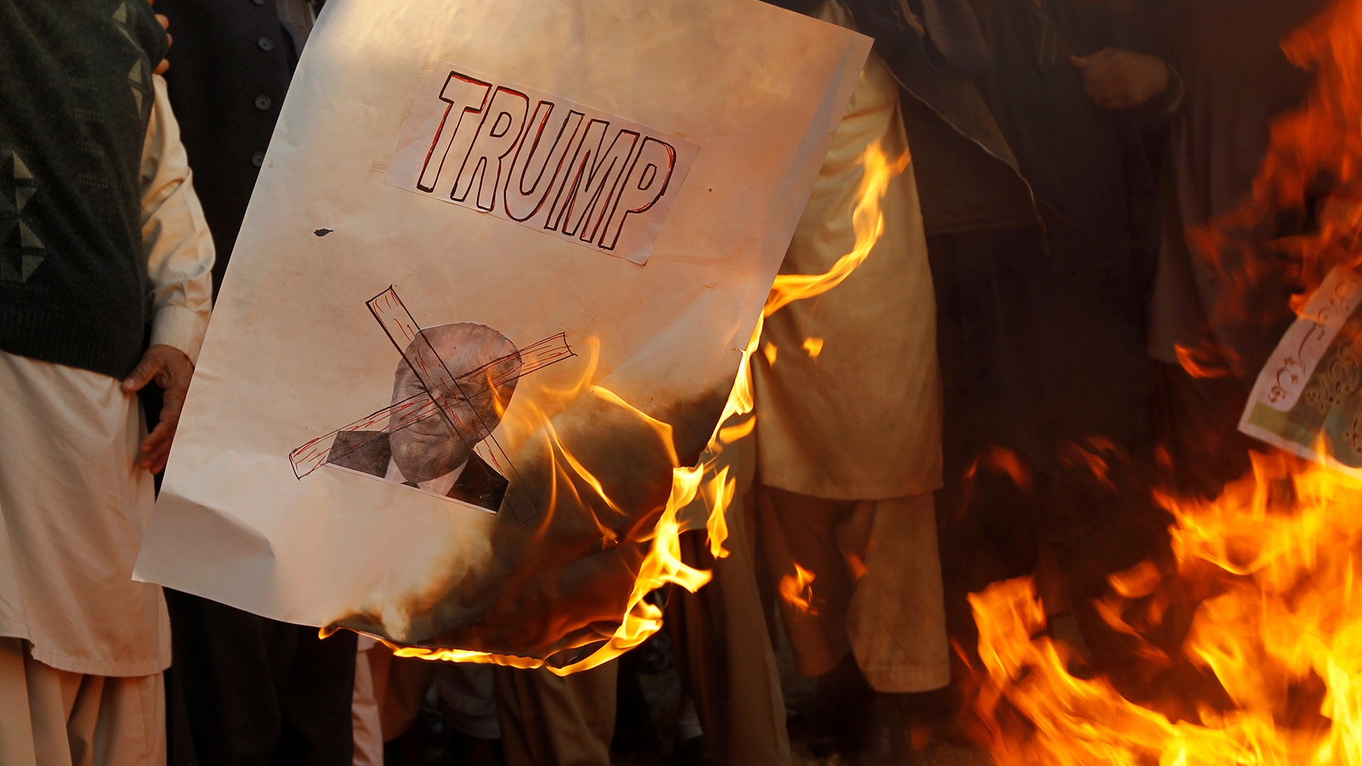 Protesters burn a picture of U.S. President Donald Trump at a protest in Islamabad, Pakistan, December 7