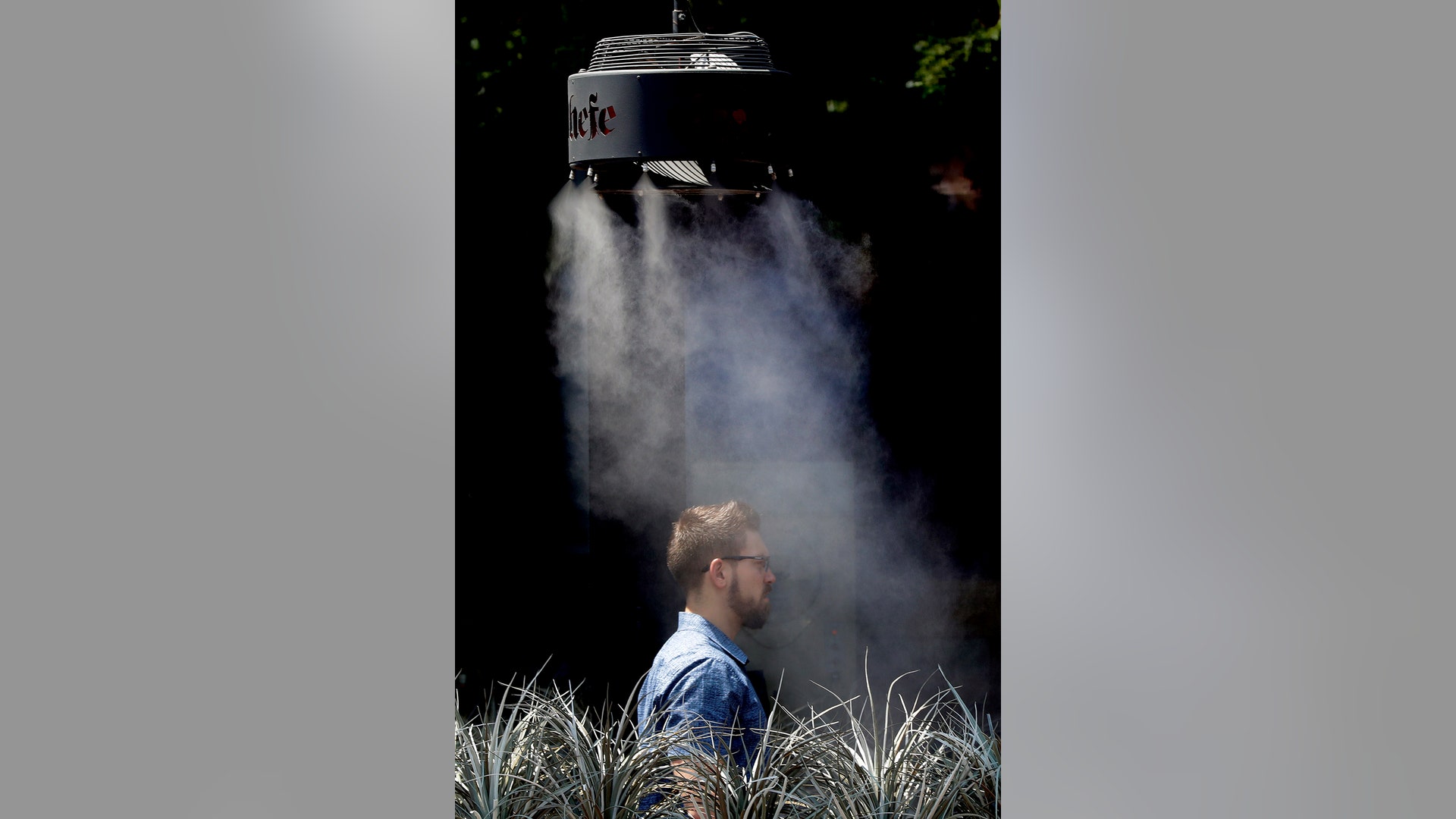 A man stands under a misting machine in Tempe, Monday