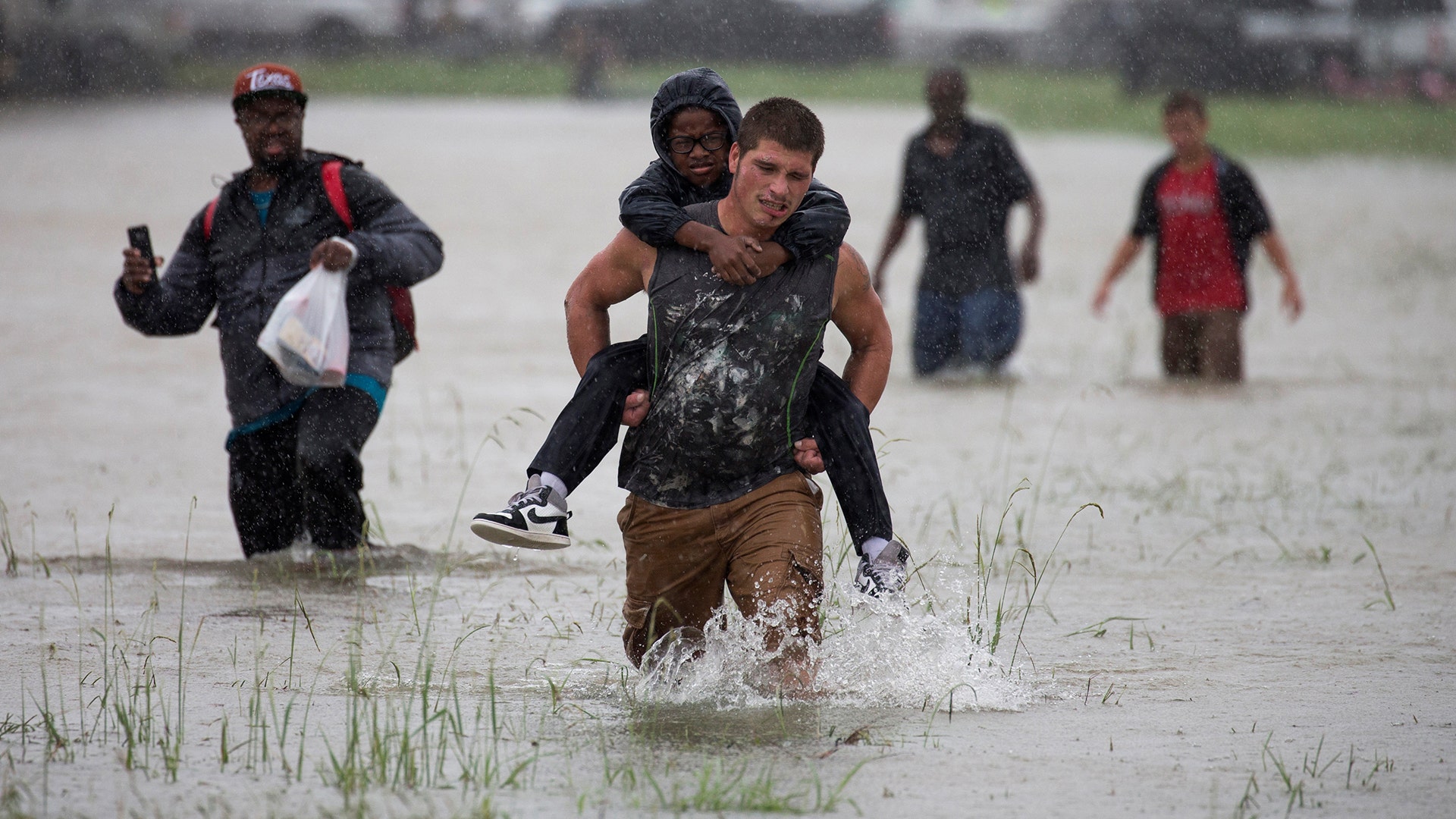 A man wades through flood waters from Tropical Storm Harvey while helping evacuate a boy in east Houston, Texas, Monday