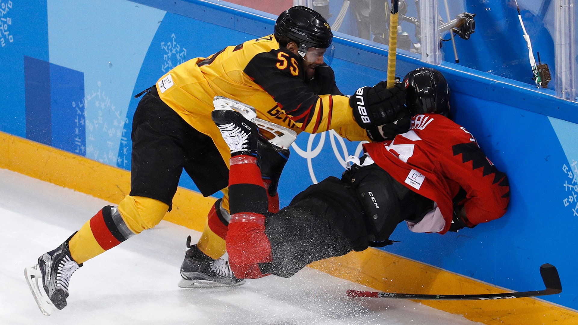 Felix Schutz of Germany hits Maxim Noreau of Canada, into the boards in their ice hockey semi-final match at the Winter Olympics