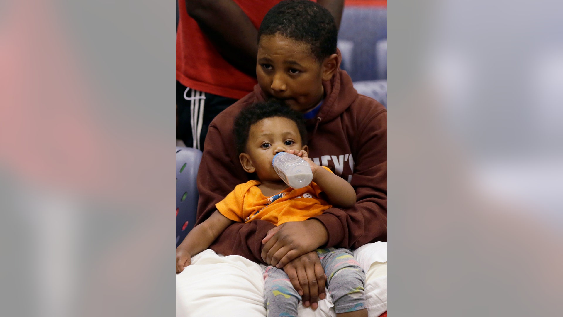 Evacuee Edward Jones, 11, holds his step-brother Mickel Duane Batts at the Lakewood Church in Houston, Tuesday