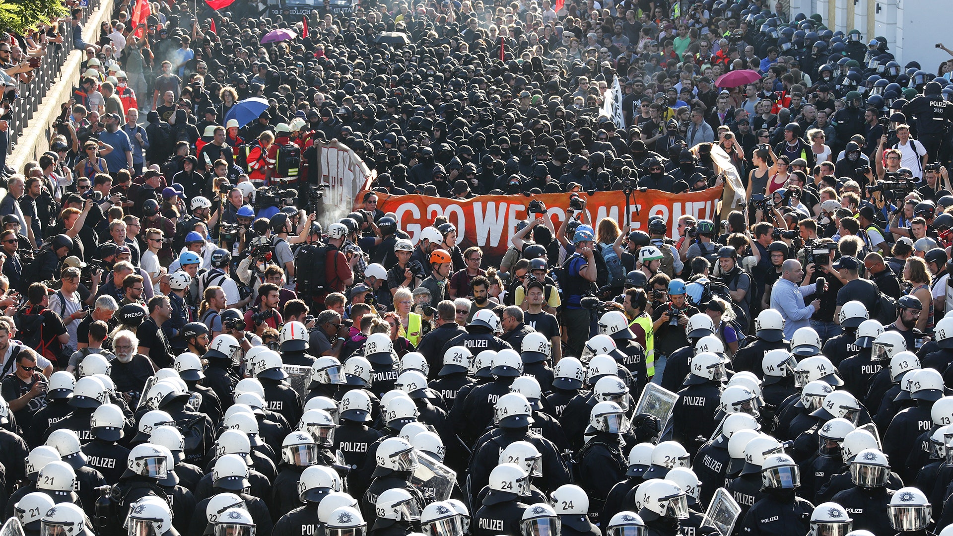 German riot police stand in front of protesters during the demonstrations at the G20 summit in Hamburg, Germany, July 6