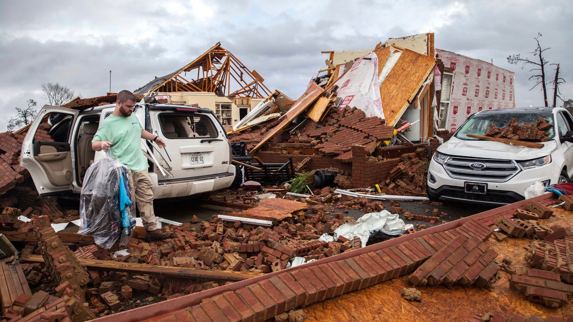 Ren retrieves clothing from a damaged car parked at a home that was hit by a tornado, Sunday, Jan. 22, 2017, in Adel, Ga.