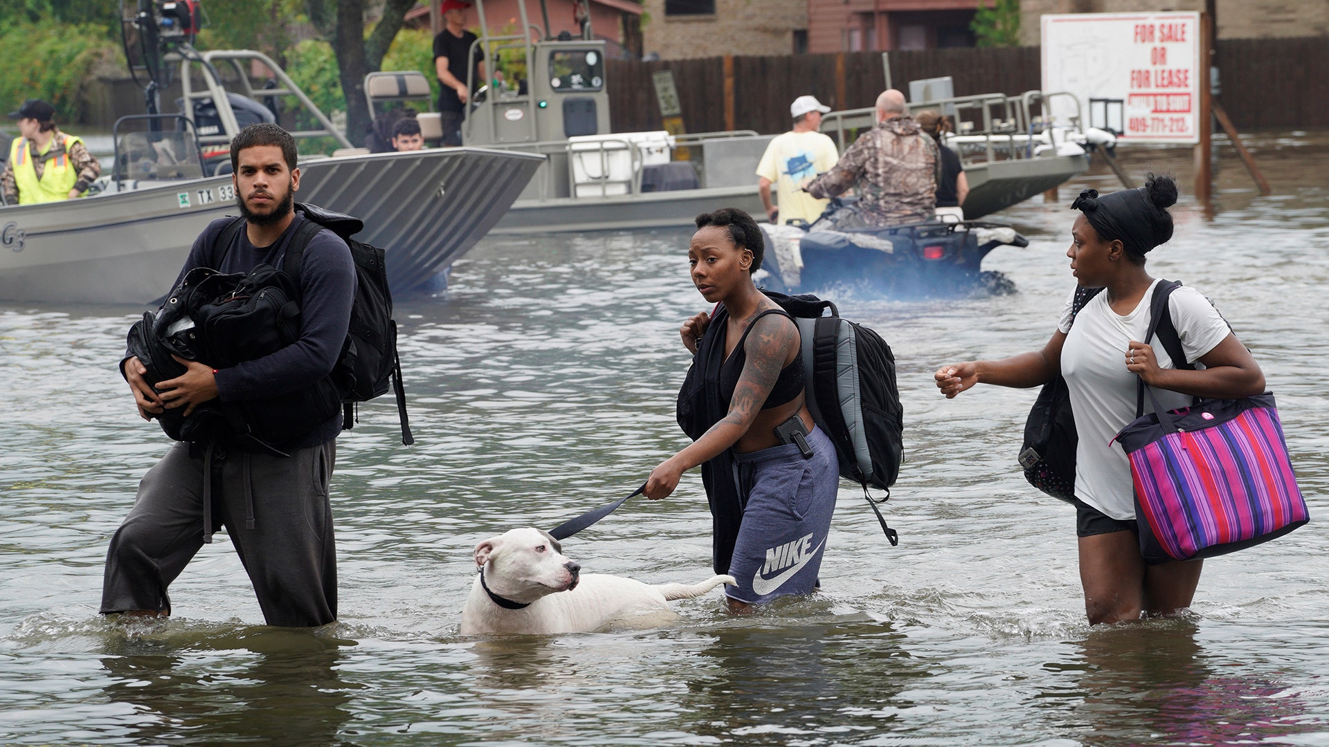 People walk through water to a staging area to evacuate from flood waters from Hurricane Harvey in Dickinson, Texas, Sunday