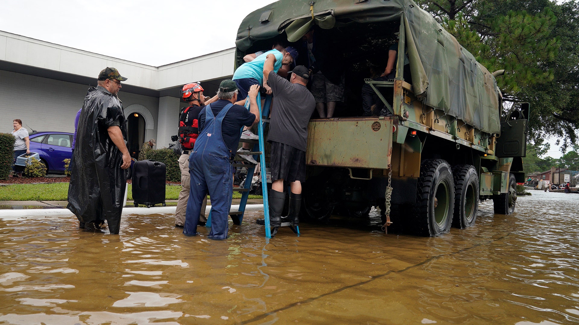 Volunteers load people into a collector's vintage military truck escaping flood waters from Hurricane Harvey in Dickinson, Texas, Sunday