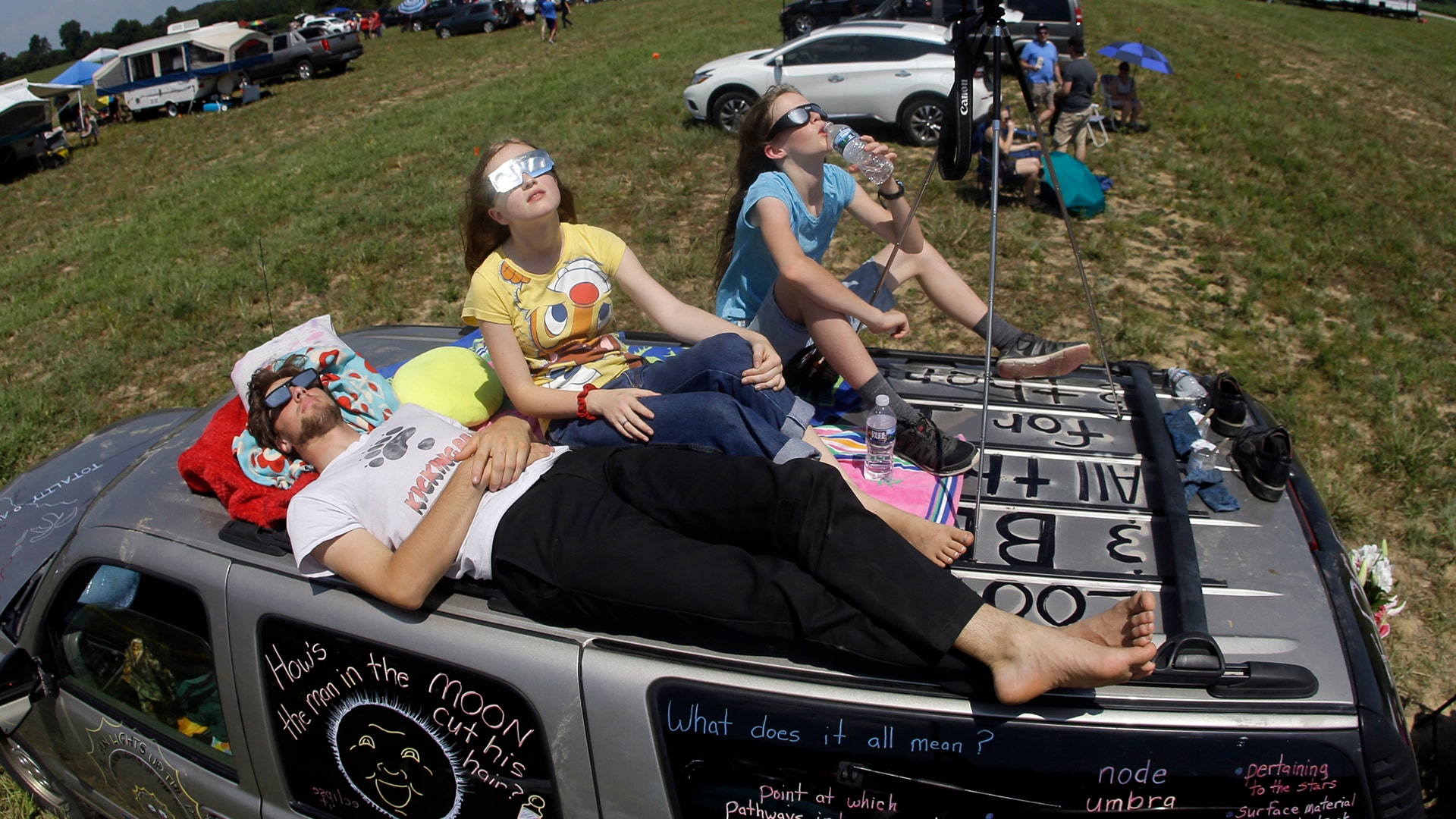 Jonathan Billing, Mary Ludwig, and Emily Ludwig, watch the solar eclipse from the roof of their vehicle in Hopkinsville, Kentucky
