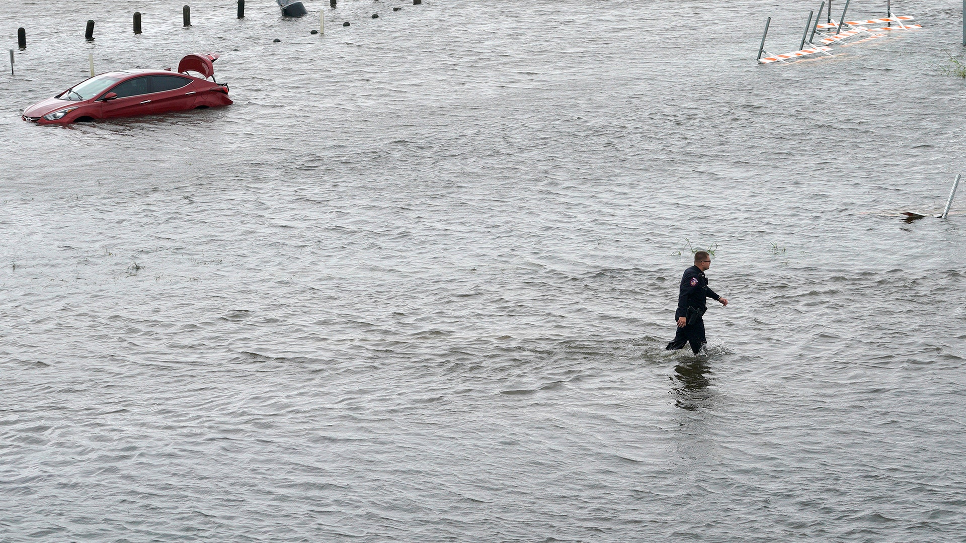 A police officer wades through the Hurricane Harvey floodwaters in Alvin, Texas, Tuesday