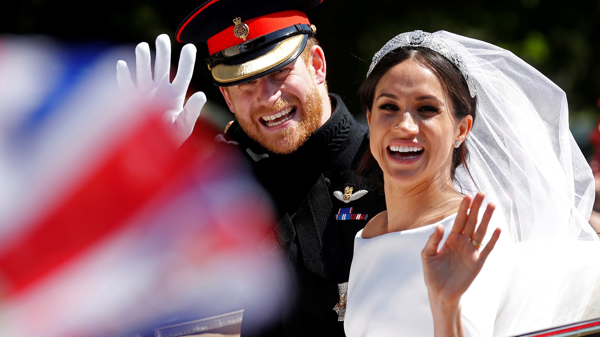 Prince Harry and his wife Meghan wave as they ride in a horse-drawn carriage after their wedding ceremony