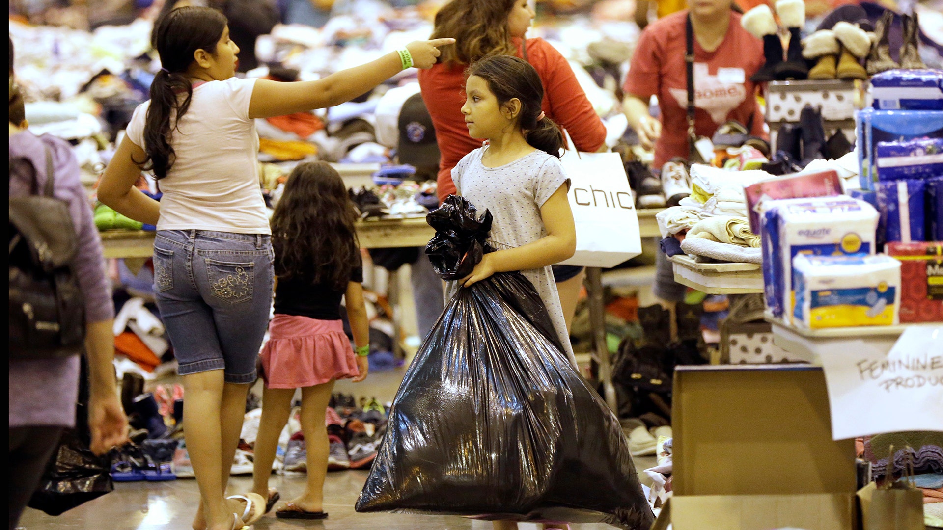 A Harvey flood evacuated child carries donated supplies in a bag at a shelter setup inside NRG Center, Wednesday, in Houston