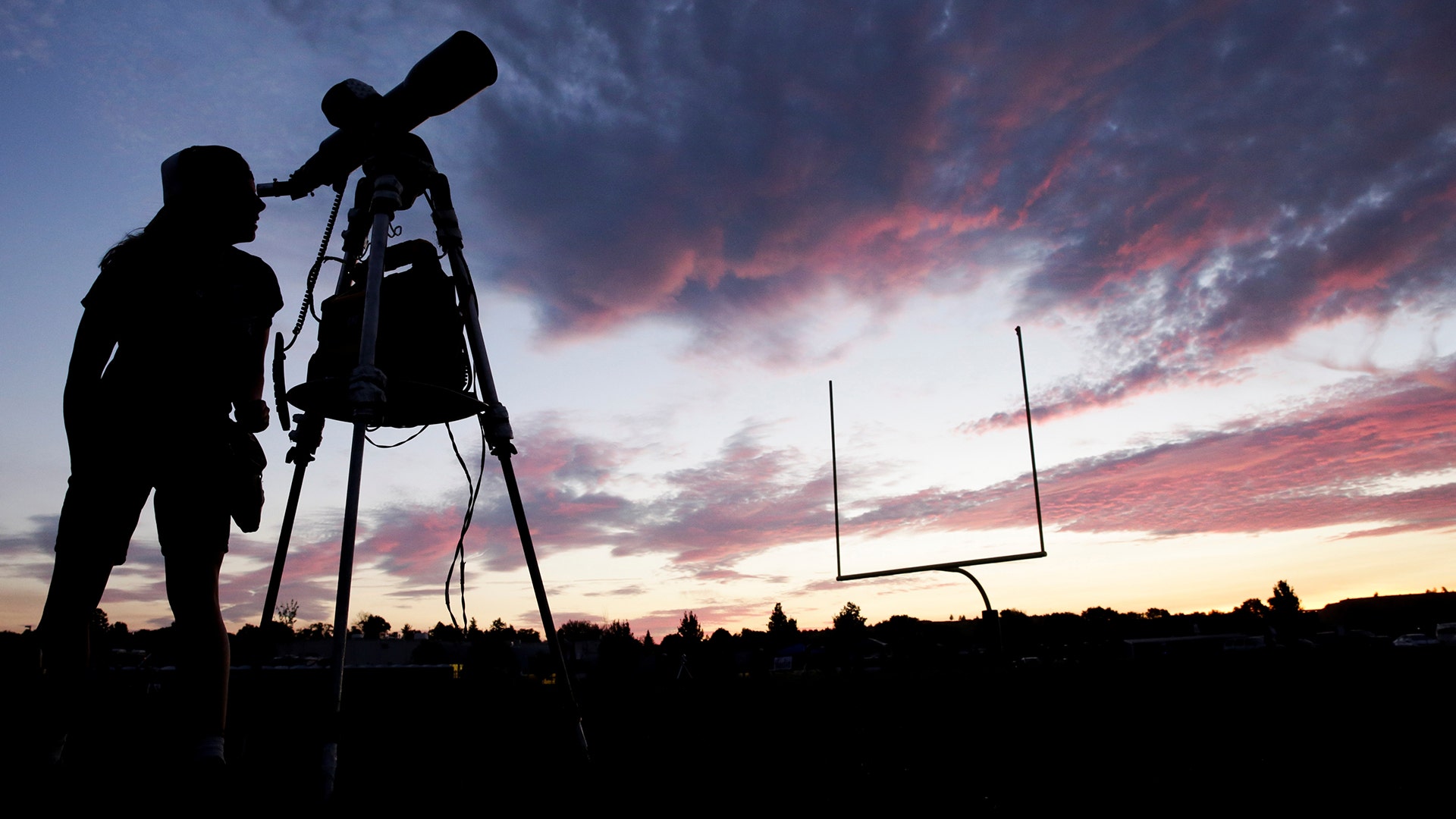 A woman looks through a telescope on the football field at Madras High School in Madras, Oregon, August 20