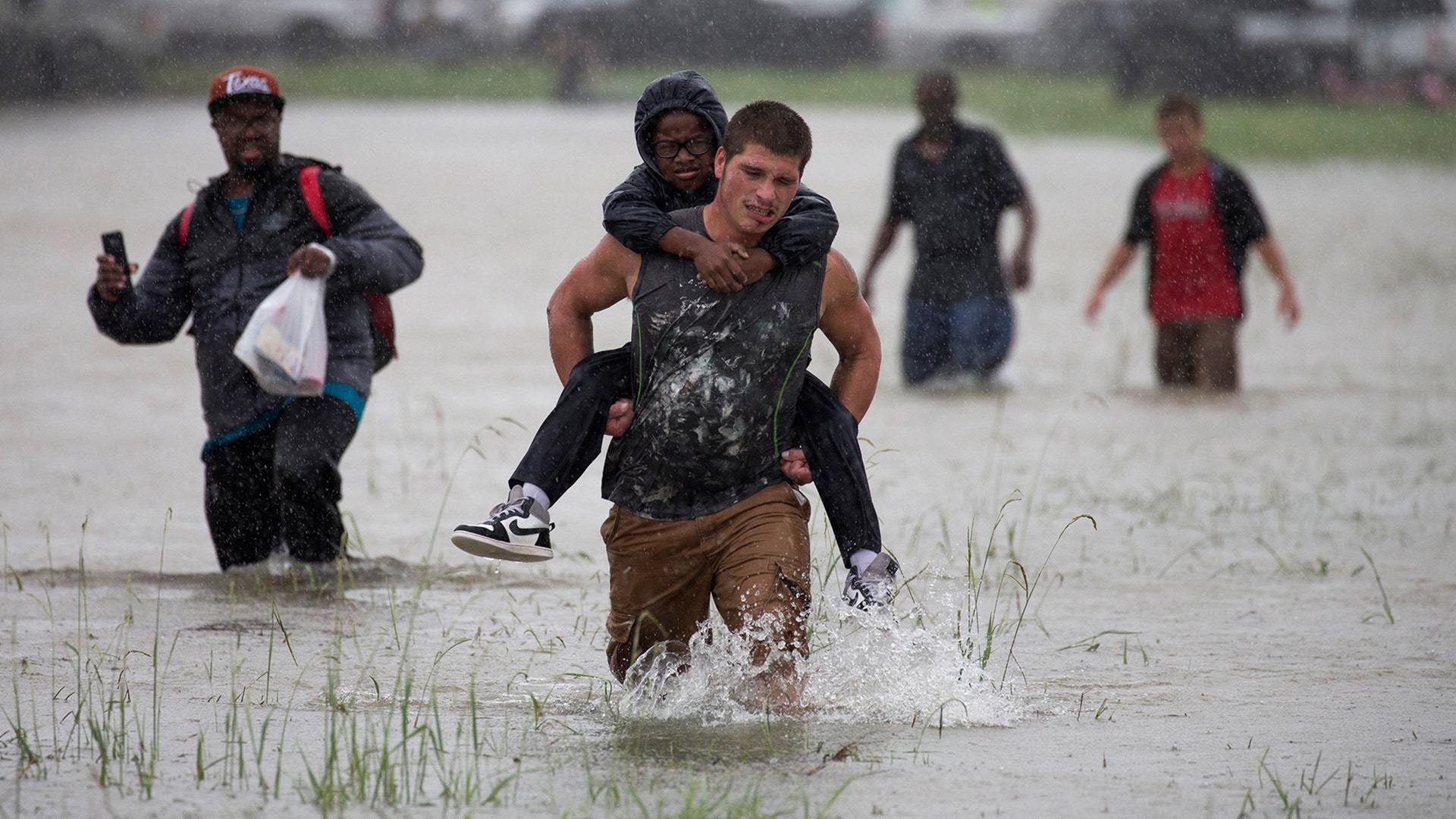 A man wades through flood waters from Tropical Storm Harvey while helping evacuate a boy in Houston, Texas, August 28, 2017