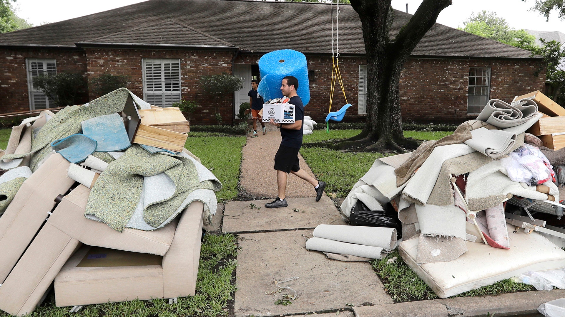 Michael Saghian helps remove items damaged by floodwaters from Tropical Storm Harvey from his home in Houston, August 30, 2017