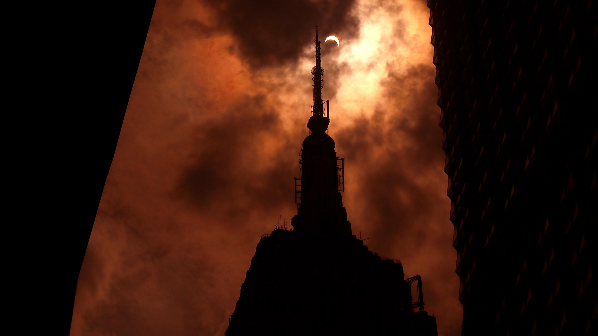 The sun is eclipsed by the moon over top of the Empire State Building in New York City, August 21