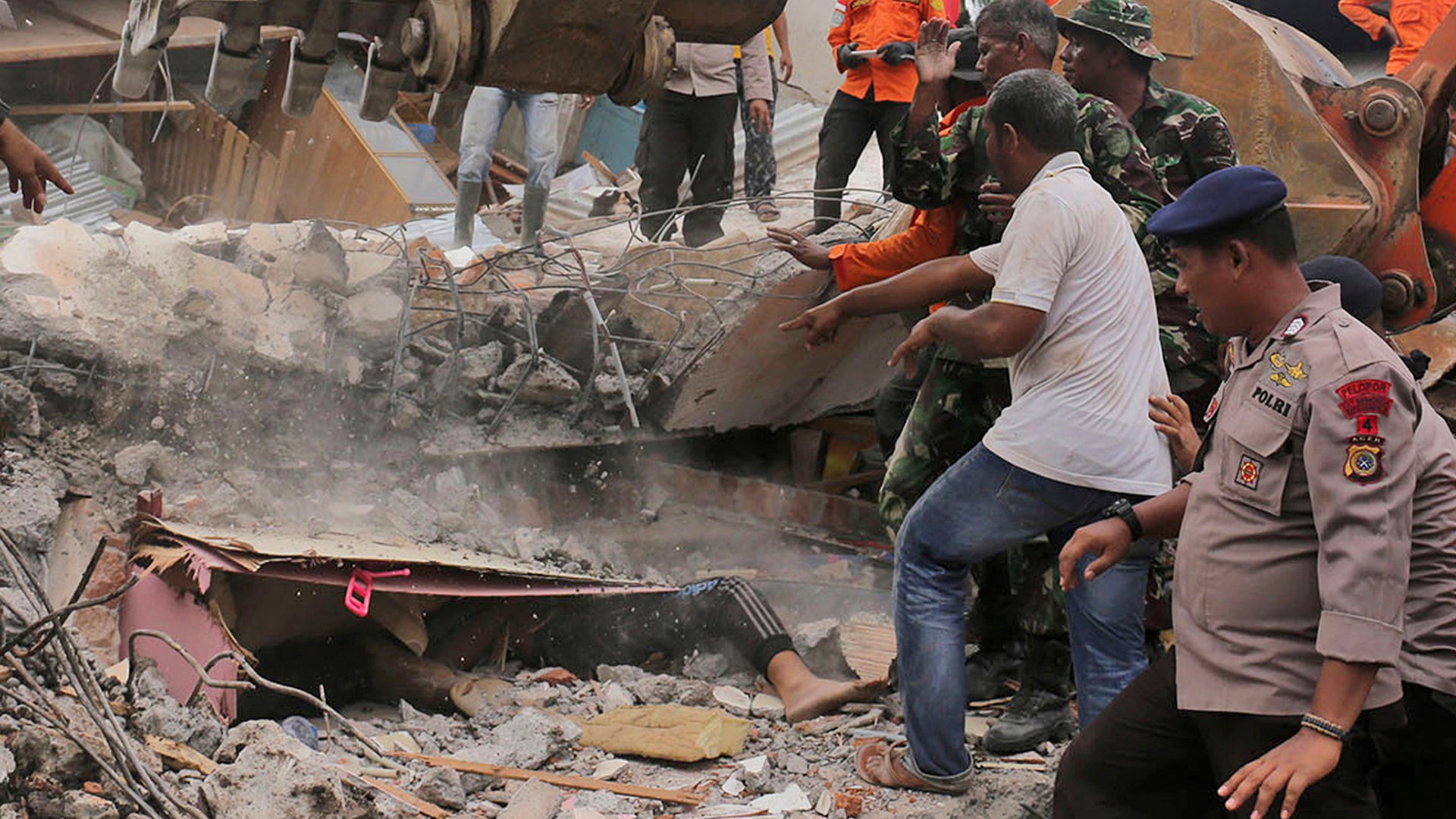 Rescuers recover the body of a victim from a collapsed building after an earthquake in Pidie Jaya, Aceh province, Indonesia.