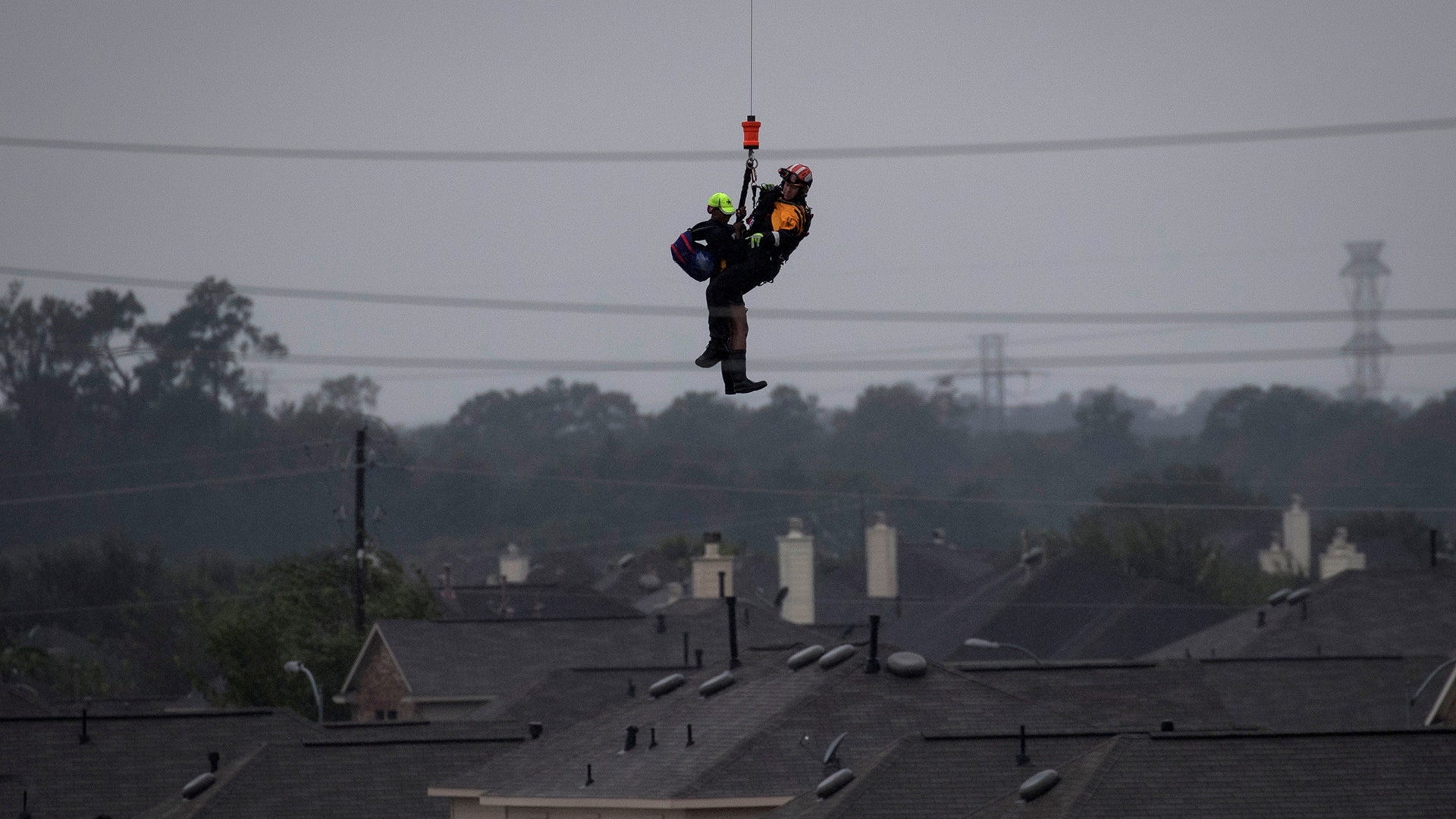 A military helicopter and personnel rescue a stranded resident from floods caused by Tropical Storm Harvey in east Houston, Tuesday