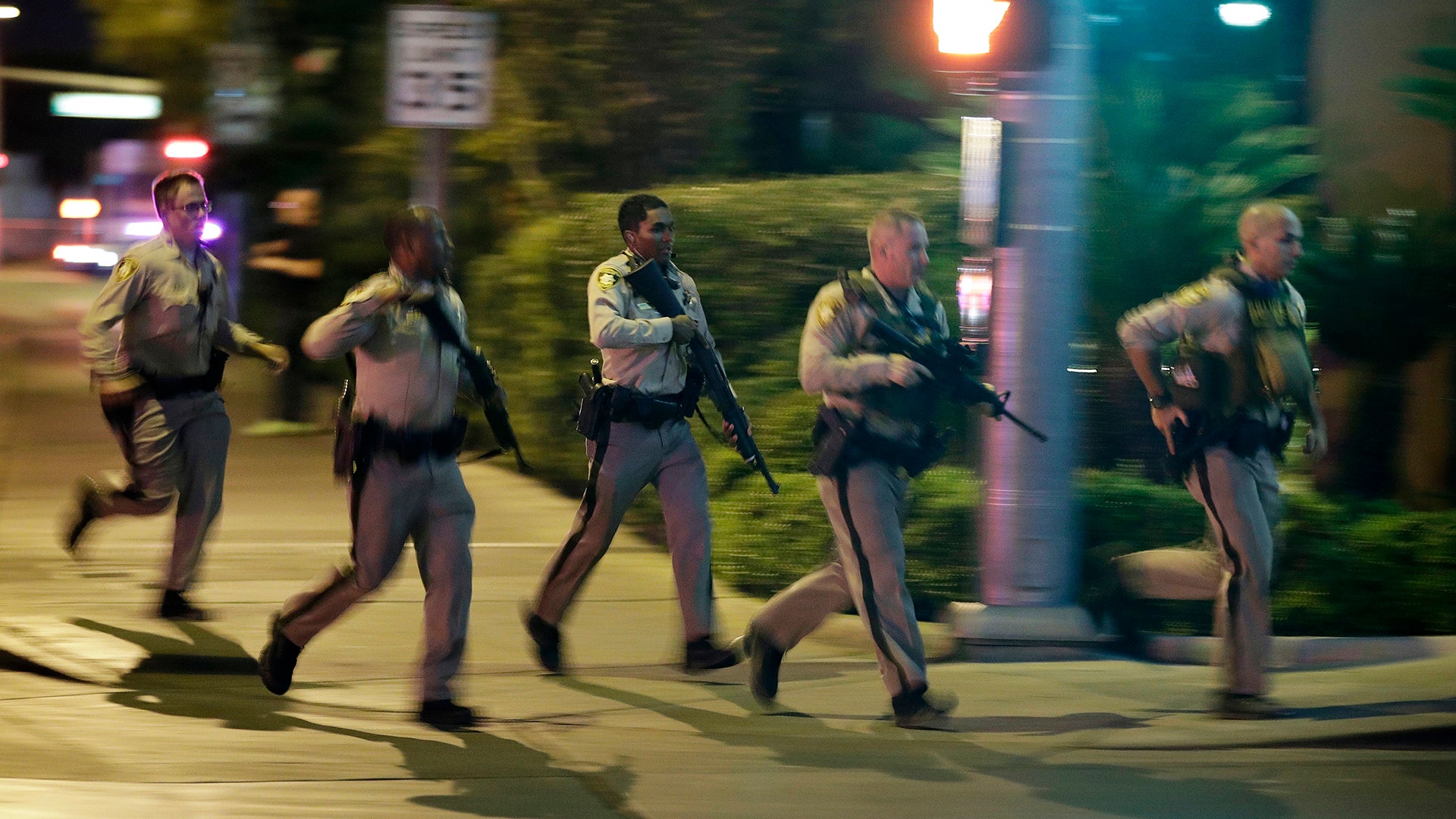 Police run to cover at the scene of a shooting near the Mandalay Bay resort and casino on the Las Vegas Strip, Sunday