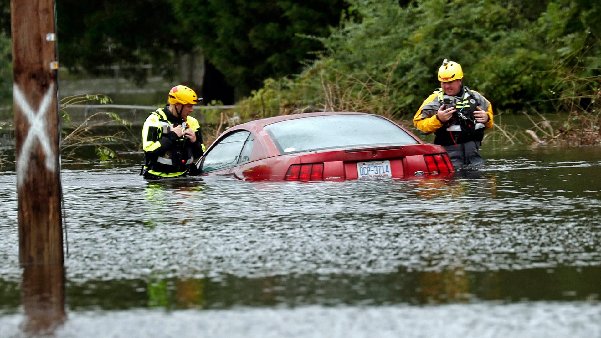 Members of a rescue team check a submerged vehicle stranded by floodwaters in New Bern, North Carolina, Saturday