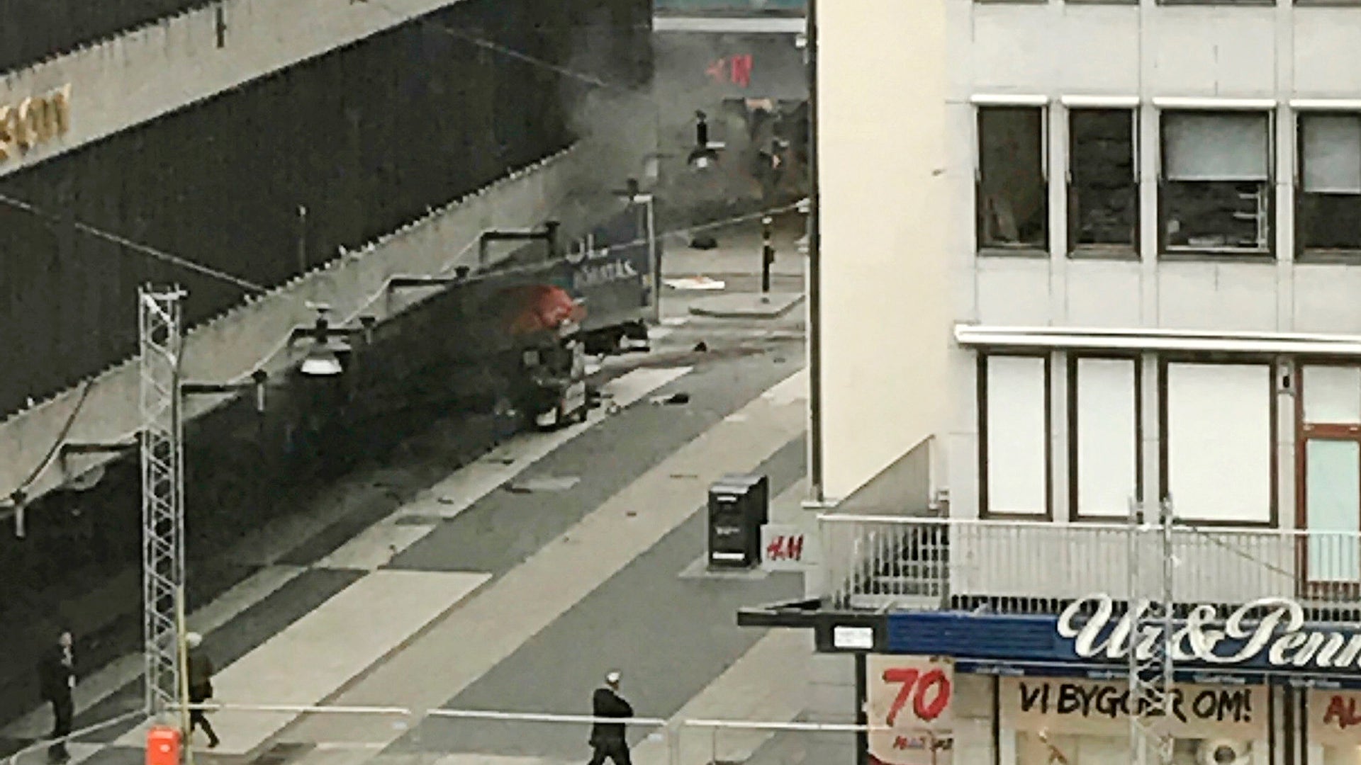 Witnesses observe the scene after a truck crashed into a department store in central Stockholm