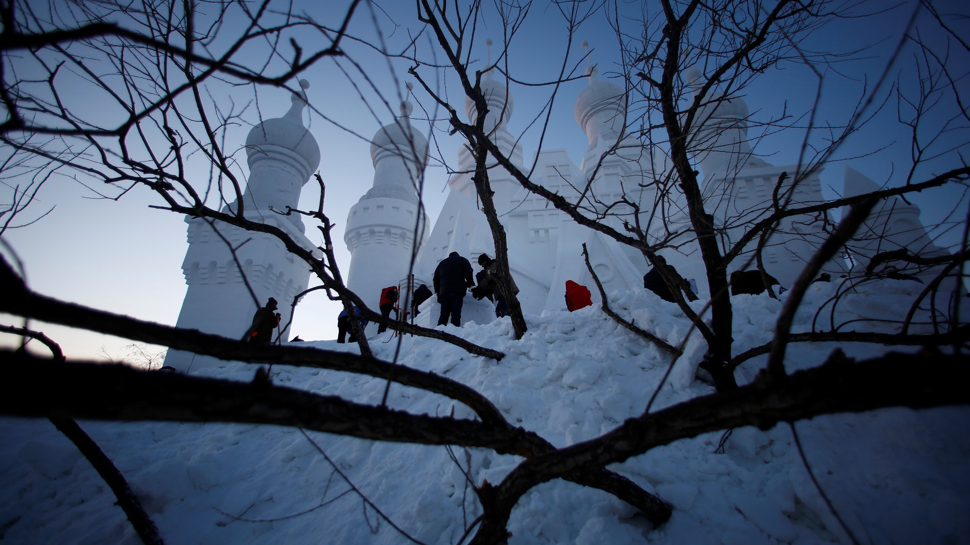 Artists and workers prepare a snow sculpture. 