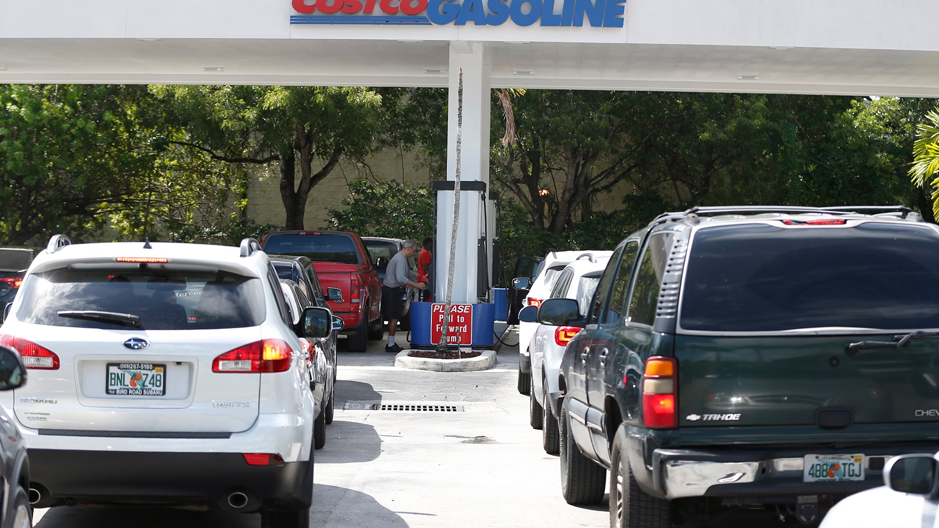 Long lines of cars stretch out into the street as people wait to pump gas at a Costco gas station in North Miami, Wednesday
