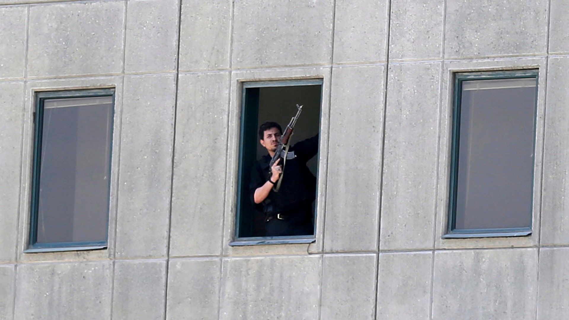 An armed man stands in a window of the parliament building in Tehran