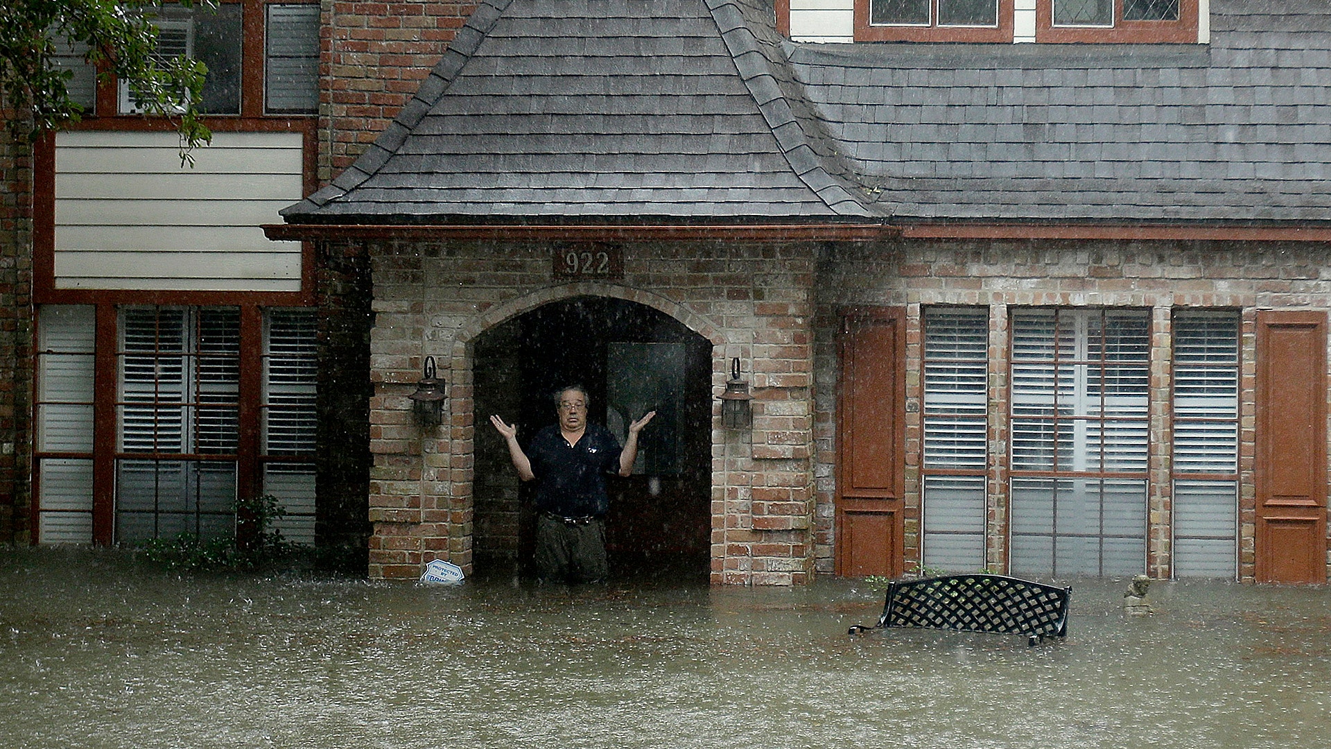 A man standing in the doorway of his flooded home responds to an evacuation offer in a neighborhood in Houston, Monday