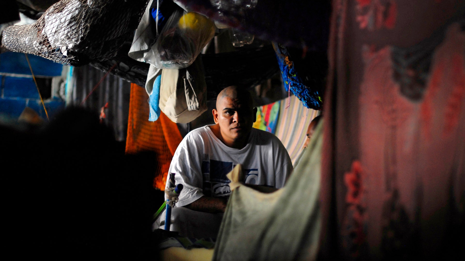 A member of the Mara Salvatrucha gang listens to a priest in his cell at the prison of Ciudad Barrios